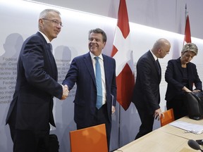 Axel Lehmann, Chairman Credit Suisse, left, and Colm Kelleher, Chairman UBS, shake hands beside Swiss Federal President Alain Berset and Swiss Finance Minister Karin Keller-Sutter, at the end of a press conference in Bern, Switzerland, Sunday March 19, 2023. Banking giant UBS is acquiring its smaller rival Credit Suisse in an effort to avoid further market-shaking turmoil in global banking, Swiss President Alain Berset announced on Sunday.