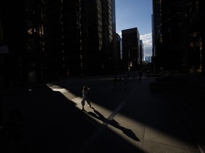 Pedestrians walk through a sliver of sunlight in the financial district in downtown Toronto on Wednesday July 6, 2022. ISS Corporate Solutions, Inc. says for the first time ever women hold one third of the board director positions across companies listed on the S&P/TSX composite.