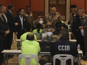In this photo release by Thailand Cyber Crime Investigation Bureau, policemen talk to suspects, wearing light green shirt and sitting back to camera at left side, at Cyber Crime Investigation Bureau in Bangkok, Thailand Wednesday, March 22, 2023. Thai police announced Wednesday they have busted a gang that operated call centers to deceive elderly U.S. citizens into wiring them money, netting more than 3 billion baht ($87 million). (Thailand Cyber Crime Investigation Bureau via AP)