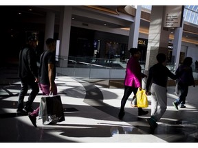 Shoppers carry bags while walking at a mall in Garden City, New York. Photographer: John Taggart/Bloomberg