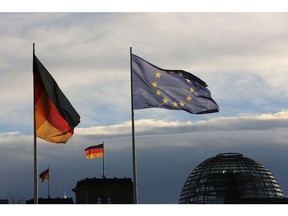 The German national flag flies beside a European Union (EU) flag outside the Chancellery in Berlin, Germany, on Friday, Nov. 18, 2016. Germany's Chancellor Merkel said she's ready to work with U.S. President-elect Donald Trump and won praise for her leadership from U.S. President Barack Obama, who suggested Germans would do well to re-elect her next year. Photographer: Krisztian Bocsi/Bloomberg