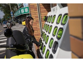 A woman removes a Gogoro Inc. battery from a charging station in Taipei, Taiwan, on Monday, Jan. 22, 2018. Gogoro, the Taiwanese electric scooter maker backed by former U.S. Vice President Al Gore, sees the smog-choked streets of Southeast Asia as the ideal target market as it embarks on a quest to expand its business overseas.