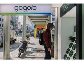 A man stands next to a Gogoro Inc. battery charging station outside one of the company's stores in Taipei.