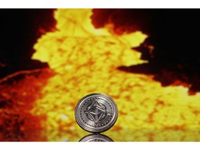 A coin representing Ethereum cryptocurrency sits reflected on a polished surface and photographed against an image of liquid metal as it flows from a blast furnace in this arranged photograph in London, U.K., on Thursday, Feb. 8, 2018. Cryptocurrencies tracked by Coinmarketcap.com have lost more than $500 billion of market value since early January as governments clamped down, credit-card issuers halted purchases and investors grew increasingly concerned that last year's meteoric rise in digital assets was unjustified.