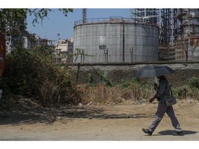 A person walks by an oil refinery operated by Bharat Petroleum Corp. Ltd., in Mumbai, India, on Tuesday, April 4, 2023. A surprise cut in oil production from OPEC+ is now setting the stage for other producers to vie for markets in Asia. Photographer: Dhiraj Singh/Bloomberg