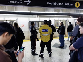 Police officers are seen on the platform as people wait for a subway train inside a Toronto Transit Commission station in downtown Toronto, Saturday, April 1, 2023.