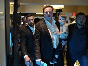 Twitter CEO Elon Musk, center, carries his child as he leaves after speaking at the POSSIBLE marketing conference, Tuesday, April 18, 2023, in Miami Beach, Fla.