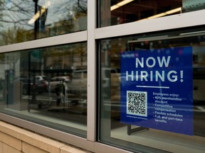An employee hiring sign with a QR code is seen in a window of a business in Arlington, Va.