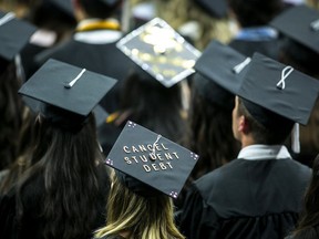 FILE - The cap of a University of Iowa graduates candidate is decorated with writing reading "Cancel student debt" during a commencement ceremony for the College of Liberal Arts and Sciences, Saturday, May 14, 2022, at Carver-Hawkeye Arena in Iowa City, Iowa. Massive tech layoffs, bank failures and a potential U.S. recession could throw a wrench in the plans of 2023 graduates -- in the same year federal student loan payments are expected to resume and accrue interest.