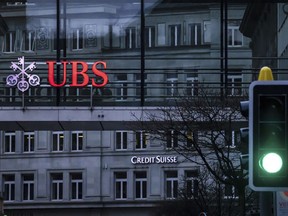 FILE - A traffic light signals green in front of the logos of the Swiss banks Credit Suisse and UBS in Zurich, Switzerland, on March 19, 2023. Swiss banking giant UBS said Tuesday it took in $28 billion of net new money for its wealth management business in the first quarter, with $7 billion of that coming in the days after the announcement of its government-backed takeover of ailing rival Credit Suisse.