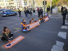 Climate activist Theodor Schnarr, second left, blocks a road with other activists during a climate protest in Berlin, Germany, Friday, April 28, 2023. Climate activists staged a tenth straight day of protests in Berlin on Friday, blocking key roads during rush hour and bringing parts of the German capital to a standstill.