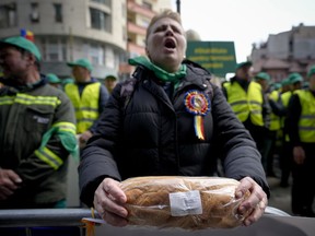 FILE - A woman holds a loaf of bread during a farmers' protest in front of the Representative Office of the European Commission in Bucharest, Romania, on, April 7, 2023. Slovakia has become the third European Union country to ban food imports from Ukraine. The move deepens a challenge for the bloc as it works to help Ukraine transport its grain to world markets. Slovakia followed Poland and Hungary, both of which announced bans Saturday on Ukrainian food imports through June 30. They did so in response to rising anger from farmers who say that a glut of grain in their countries is causing them economic hardship.