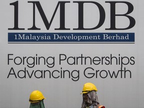 FILE - Construction workers chat in front of a billboard for state investment fund 1 Malaysia Development Berhad (1MDB) at the fund's flagship Tun Razak Exchange development in Kuala Lumpur, Malaysia, May 14, 2015. Swiss prosecutors on Tuesday, April 25, 2023 say they have indicted two managers of a Saudi oil exploration company as part of a years-long investigation of a case linked to a Malaysian sovereign wealth fund. The office of the Swiss attorney general said the two managers at PetroSaudi are accused of trying to enrich themselves and others by misappropriating at least $1.8 billion transferred to the 1Malaysia Development Berhad state fund, known as 1MDB.