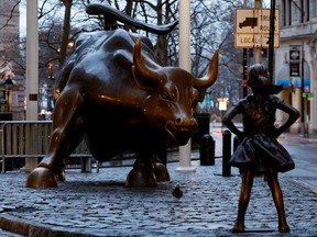 A statue of a girl facing the Wall St. Bull in the financial district in New York.