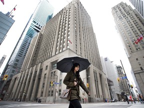 A woman walks past bank buildings in Toronto.