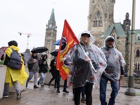 Members of the Public Service Alliance of Canada (PSAC) walk in the rain on a picket line outside the Office of the Prime Minister and Privy Council, across from Parliament Hill, as workers from Canada's largest federal public-service union are on strike across the country in Ottawa.