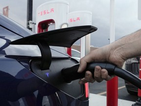 FILE - A motorist charges his electric vehicle at a Tesla Supercharger station in Detroit, Wednesday, Nov. 16, 2022. New Jersey residents looking to buy or lease an electric vehicle won't be able to get a government rebate -- at least temporarily -- because the state program has been so popular that it's already running out of money, officials said, Tuesday, April 18, 2023.