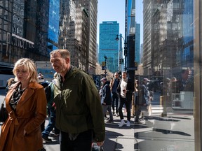 People walk through a busy midtown Manhattan, in New York City.