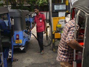 FILE- A man fills gas into a vehicle at a fuel station in Colombo, Sri Lanka, March 29, 2023. Sri Lanka's president urged lawmakers Wednesday to approve a four-year International Monetary Fund program to restructure the country's $17 billion in foreign debt.