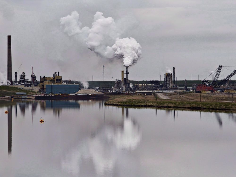 The Syncrude oil sands extraction facility is reflected in a tailings pond near Fort McMurray, Alta.
