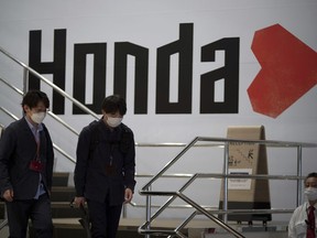 FILE - People walk near the logo of Honda Motor Company at a showroom in Tokyo, May 13, 2022. Honda is gearing up for an electrification shift in North America with two models developed with General Motors going on sale next year and a bigger EV with a new platform in 2025, a year earlier than initially announced.