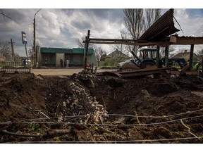 Local residents wait at a bus stop next a crater left by a missile attack in Kramatorsk, Donetsk region, on April 24. Anatolii Stepanov/AFP/Getty Images Photographer: Anatolii Stepanov/AFP/Getty Images