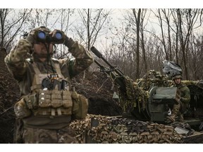 A Ukrainian serviceman (L) looks on with goggles next to another (R) sitting on an anti-air gun near Bakhmut, on March 24, 2023.  Photographer: Aris Messinis/AFP/Getty Images