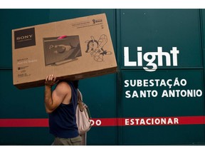 A man carries a flat screen television box past a Light SA electricity substation in Rio de Janeiro