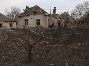 Local residents stand near a crater left by a Russian missile in Zaporizhzhia , Ukraine, Sunday, April 9, 2023. An 11-year old girl and her father were killed in the rocket attack in Zaporizhzhia.