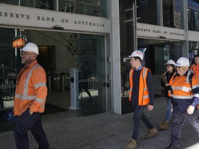 FILE - Workers in high visibility clothing walk past the Reserve Bank of Australia in Sydney, Nov. 1, 2022. Australia's central bank, on Tuesday, April 4, 2023, left its benchmark interest rate on hold at 3.6% at its latest monthly meeting on Tuesday following evidence that inflation is falling.