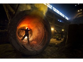 A worker carries out a burning procedure inside a ladle at Sheffield Forgemasters International Ltd., in Sheffield, U.K., on Monday, July 22, 2013.  Photographer: Jason Alden/Bloomberg
