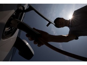 A man attaches a charging plug to a General Motors Co. (GM) Chevrolet 2017 Volt hybrid electric vehicle (EV) at a charging station in Jeju, South Korea, on Wednesday, June 14, 2017. The election of Moon Jae-in as South Korea's new president implies a shift in the nation's approach to energy, as he supports policies that favor natural gas and renewables at the expense of nuclear and coal, according to Bloomberg New Energy Finance. Photographer: SeongJoon Cho/Bloomberg