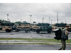 A Louisiana Army National Guard soldier passes in front of High Mobility Multipurpose Wheeled Vehicles (Humvees) and rescue boats ahead of Hurricane Laura in Lake Charles, Louisiana, U.S., on Wednesday, Aug. 26, 2020. BWX's small reactors could be used to help power disaster relief efforts. Photographer: Bryan Tarnowski/Bloomberg