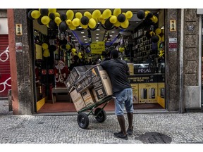 A worker holds a cart of products in front of a store on Black Friday in Rio de Janeiro, Brazil, on Friday, Nov. 25, 2022. Black Friday arrives as the traditional kickoff to Christmas shopping with year as a departure from 2021, when consumers splurged after pulling back during the pandemic.
