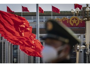 A member of the Chinese People's Armed Police Force stands guard as a Chinese national flag flies over Tiananmen Square along with other red flags ahead of the fifth plenary session of the First Session of the 14th National People's Congress (NPC) in Beijing, China, on Sunday, March 12, 2023. China reappointed several top economic officials in a leadership reshuffle Sunday, giving investors greater continuity as Beijing overhauls financial regulation and grapples with escalating tensions with the US. Photographer: Qilai Shen/Bloomberg