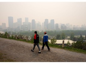 Pedestrians pass buildings shrouded in smoke from wildfires in Calgary, Alberta, Canada, on Wednesday, May 17, 2023. Scenes in Calgary were reminiscent of Seattle last summer and San Francisco in 2020 as wind currents blew smothering wildfire smoke into those population centers, compromising air quality.