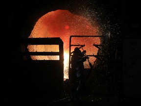 An employee takes the temperature measurement of molten iron at a steel plant in Germany.