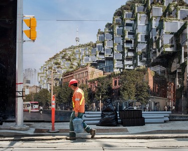 A construction worker walks past a mural on a future building on Toronto's King Street West.
