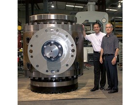 Matt Mogas (left) and Louis Mogas (right) pose next to a large MOGAS ball valve