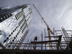 A construction worker erects scaffolding on a condominium building under construction in downtown Montreal. The construction industry has a shortage of workers.
