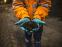 A worker holds copper concentrate at a mine in Peru.