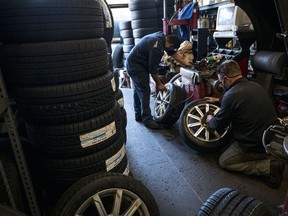 Employees wearing protective masks adjust the balance of tires at a Goodyear auto service location in South San Francisco.