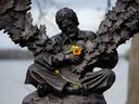 Flowers sit in the arms of the statue of Gordon Lightfoot in Orillia, Ont., after the Canadian singer-songwriter died this week at the age of 84.