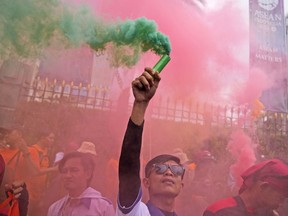 A worker holds up a smoke stick during a May Day rally in Jakarta, Indonesia, Monday, May 1, 2023. Workers and activists across Asia are marking May Day with protests calling for higher salaries and better working conditions, among other demands.