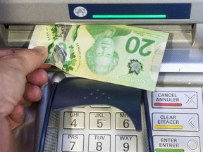 Money is removed from a bank machine in Montreal on May 30, 2016.