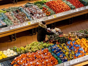 A person pushes a shopping cart through the produce section of a grocery store in Toronto.