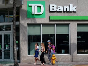People walk past a Toronto-Dominion Bank branch in Miami Beach, Florida.