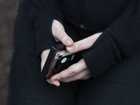 File - A teenager holds her phone as she sits for a portrait near her home in Illinois, on Friday, March 24, 2023. The U.S. Surgeon General is warning there is not enough evidence to show that social media is safe for young people -- and is calling on tech companies, parents and caregivers to take "immediate action to protect kids now."