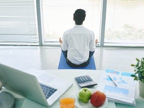 A businessman doing yoga in his office