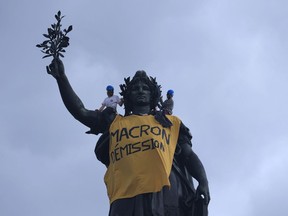 Activists draped the statue on Place de la Republique with a banner reading "Macron resign" during a demonstration, Monday, May 1, 2023 in Paris. French unions plan massive demonstrations around France to protest President Emmanuel Macron's recent move to raise the retirement age from 62 to 64.